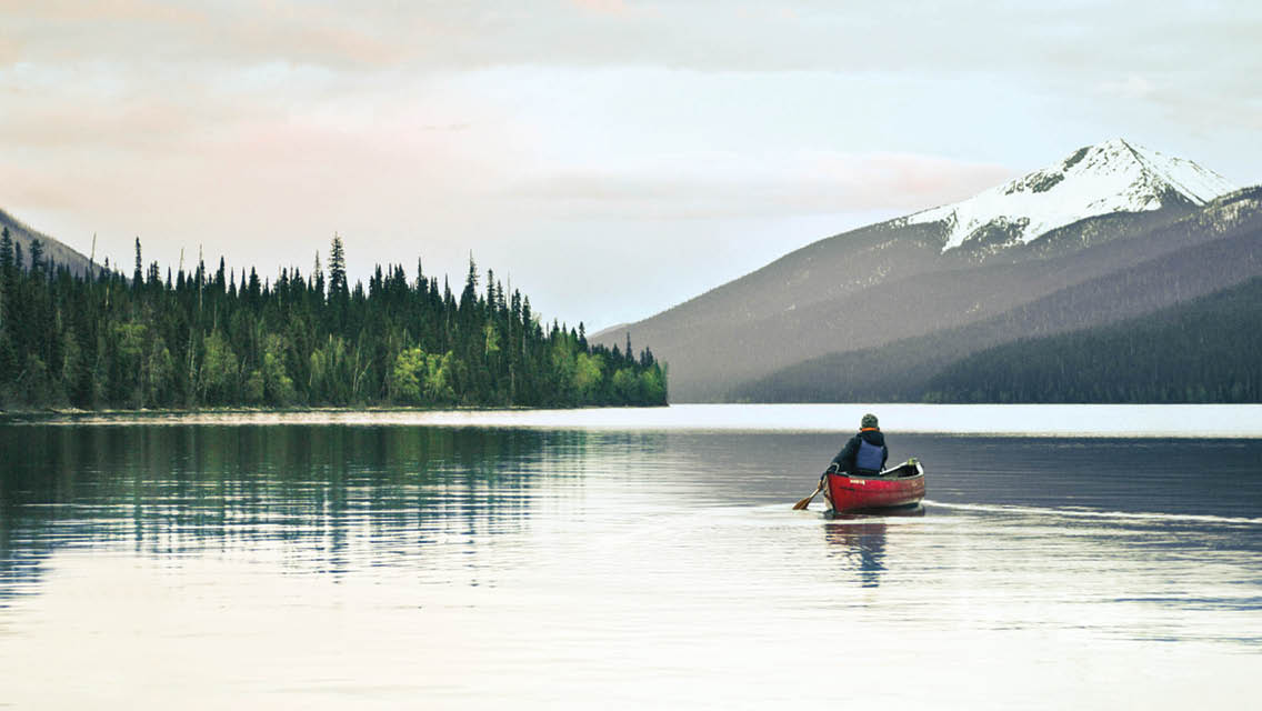 a person canoes across a mountain lake