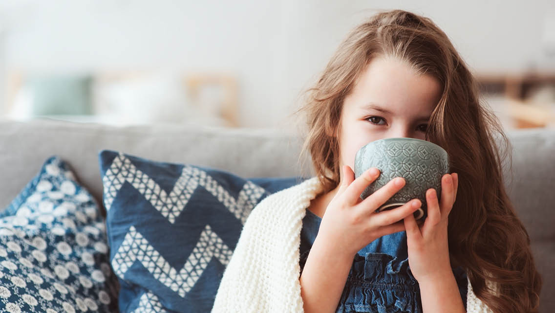 a young girl drinks a cup of tea