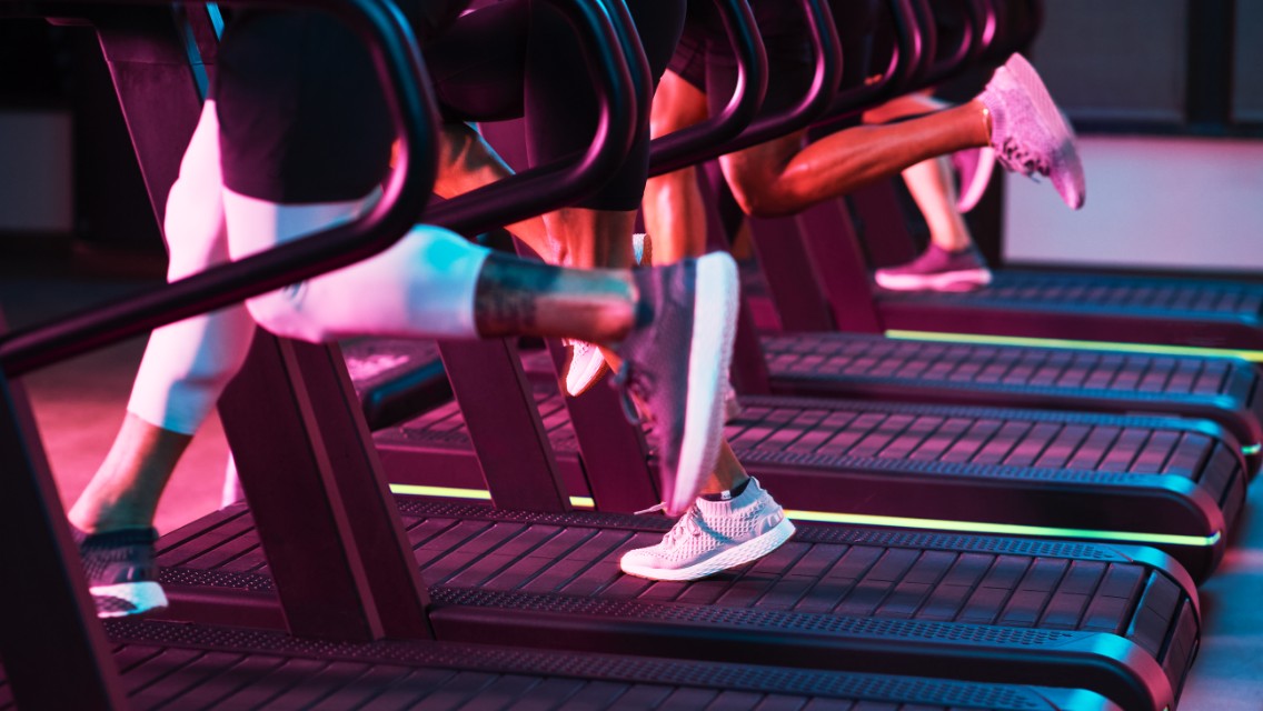 The legs of individuals who are sprinting on treadmills.