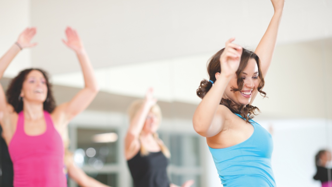 A group of women dancing in a fitness setting.