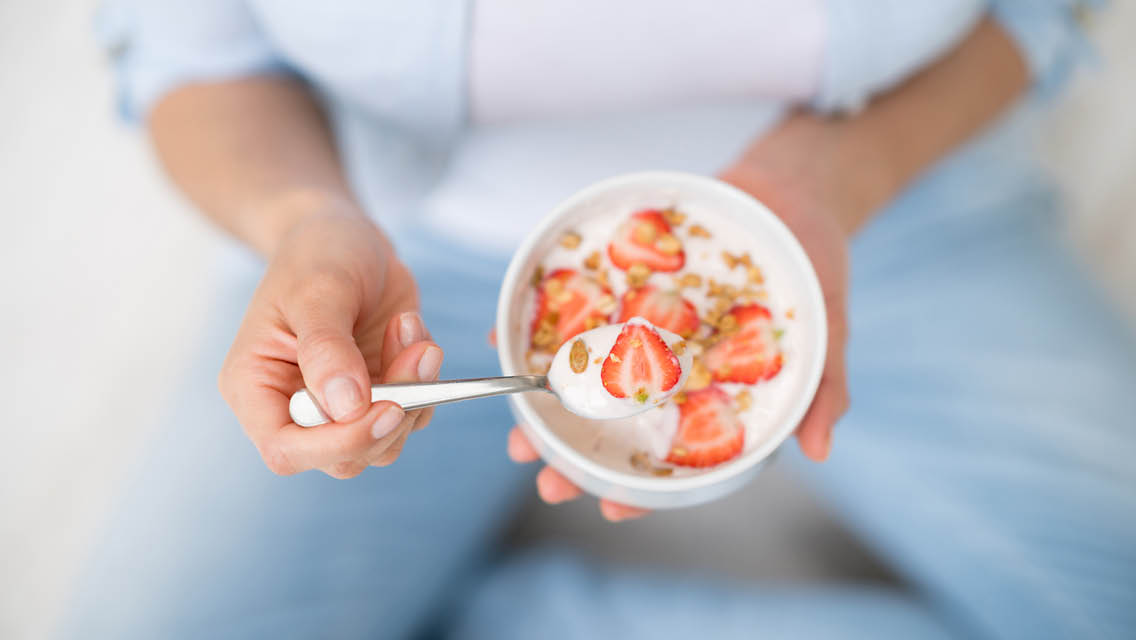 a person eating oatmeal with strawberries