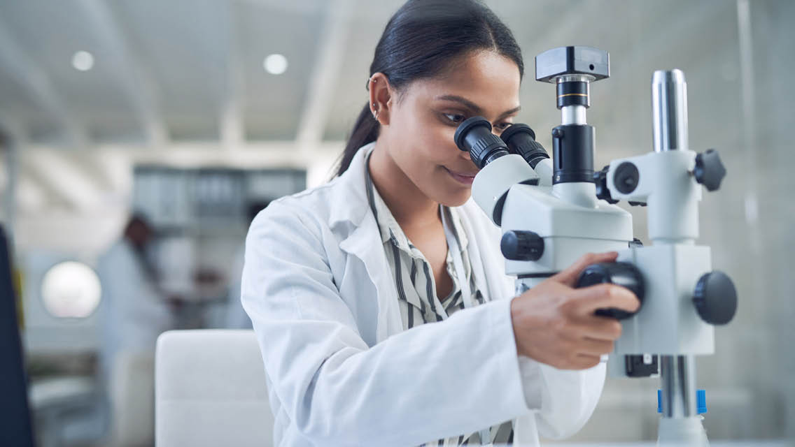 a scientist looks through a microscope