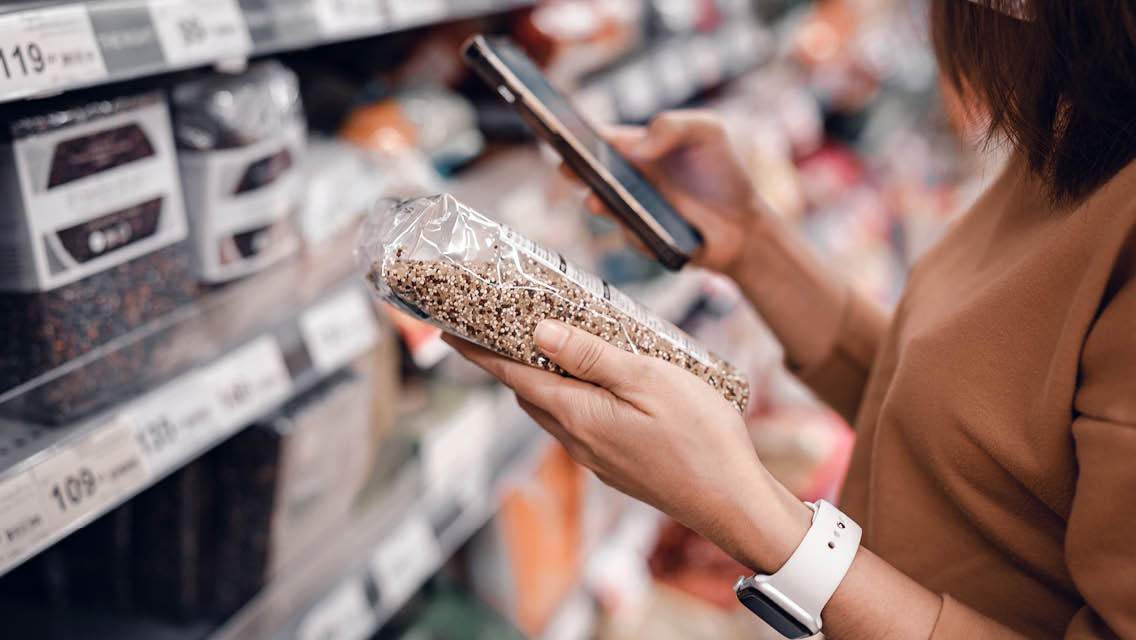 a woman scans a bag of lentils while shopping
