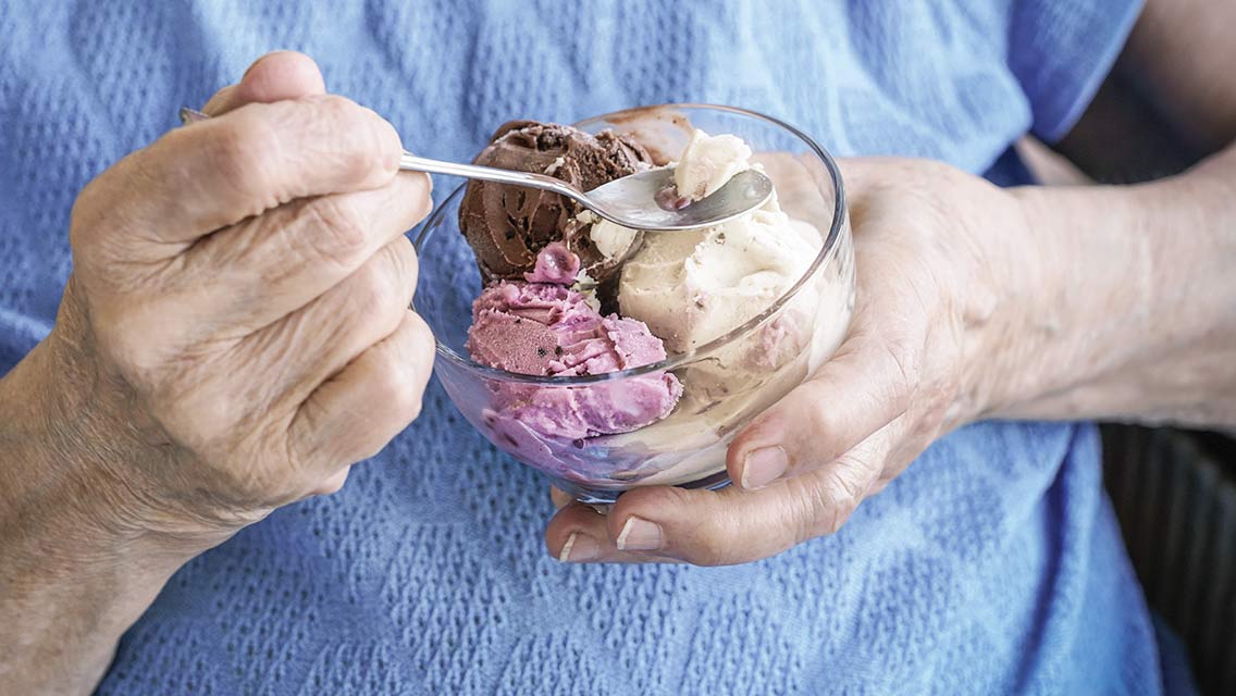 an elderly woman eats ice cream