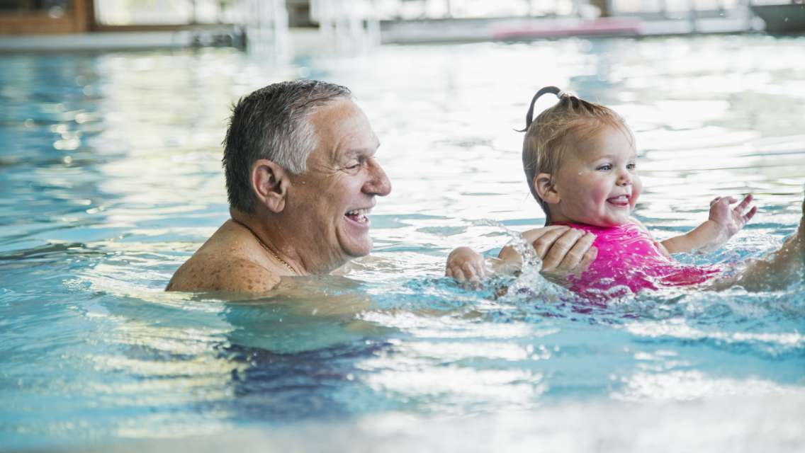 A grandparent and child swimming in the pool together.