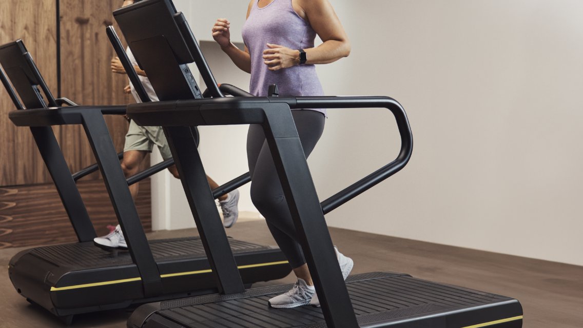Two people next to each other on treadmills in a Life Time health club.