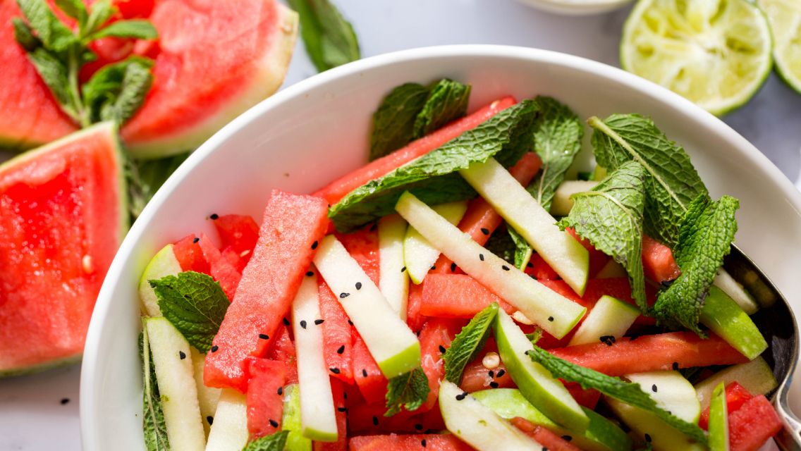 A bowl of a salad featuring watermelon, cucumber and herbs.