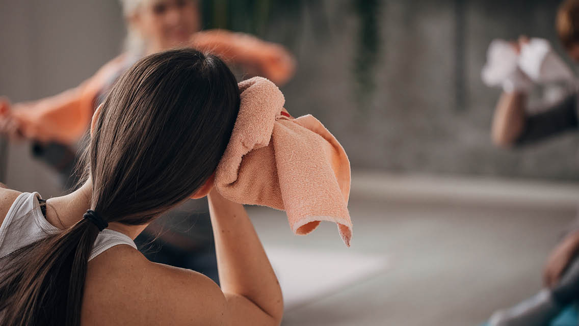 a woman wipes her head during a fitness class