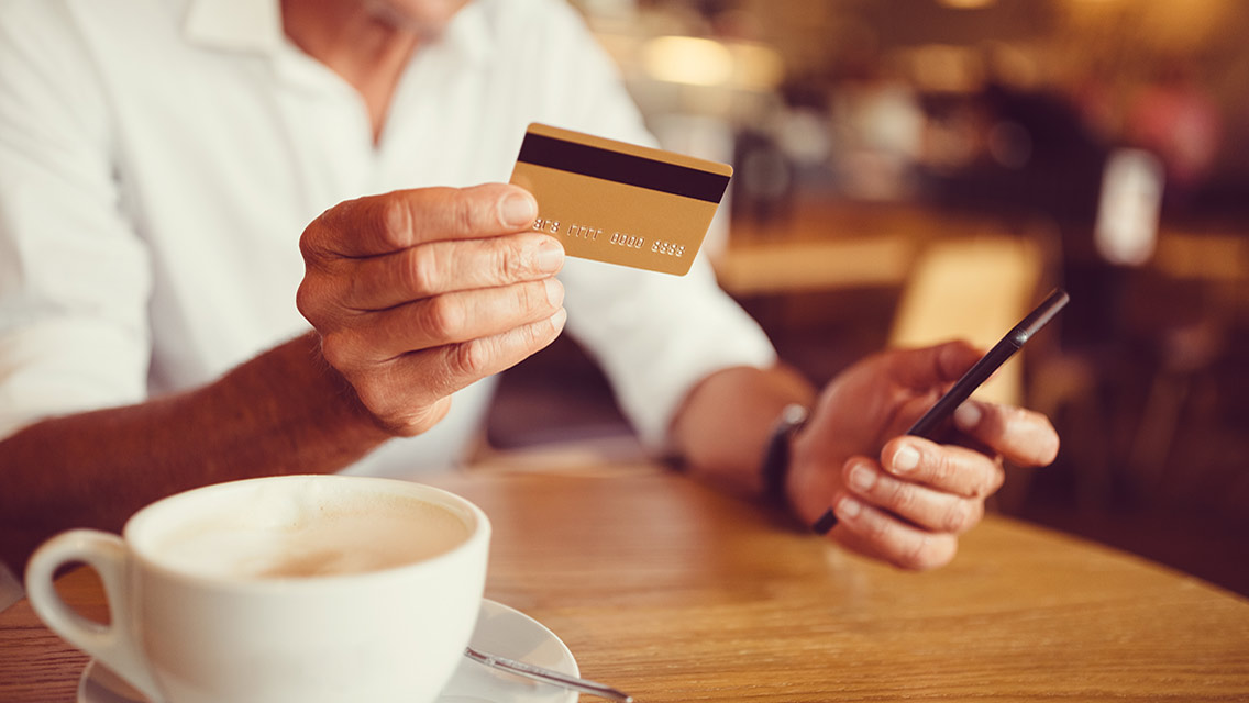 a man sits at a coffee shop paying his bill with a credit card