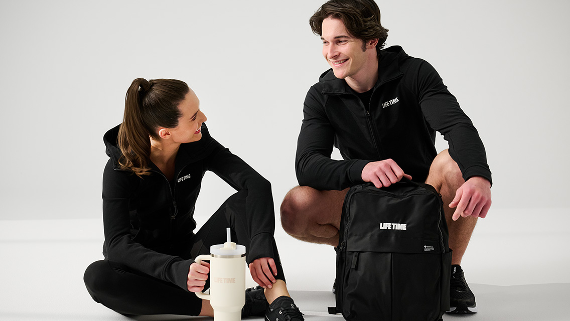 two members smiling and looking at each other with Life Time branded gear