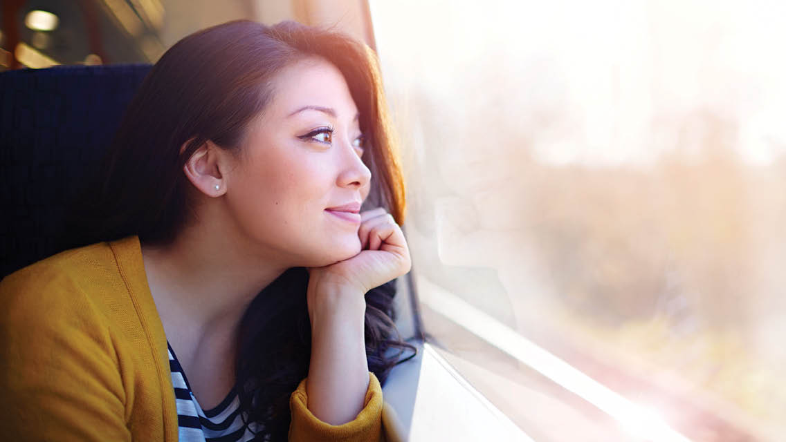a woman looks blissfully out a bus window