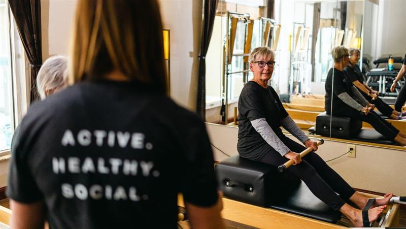 An active, older woman in a Pilates class on a Pilates reformer at Life Time.