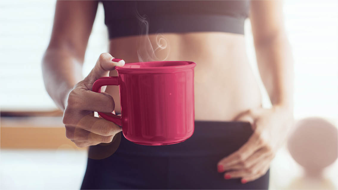 a woman in workout apparel holds a cup of coffee