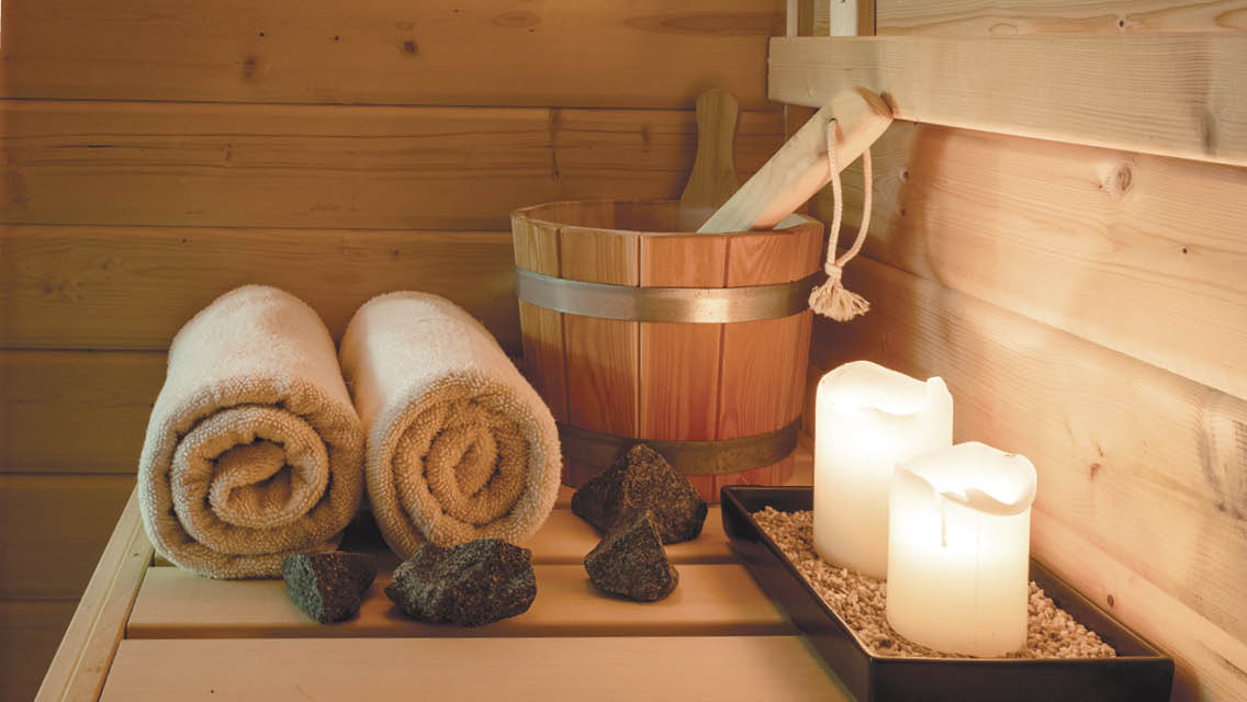 candles, towels and rocks sit on a sauna bench
