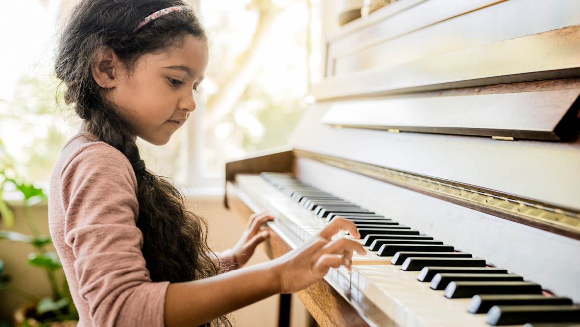 a young girl plays the piano