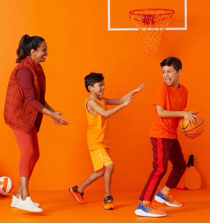 A mom with two younger boys playing basketball.