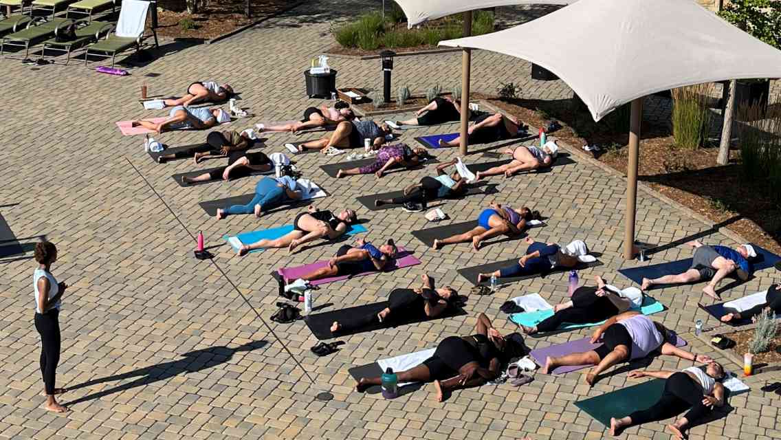 Members laying outside on yoga mats at the ARORA sunshine yoga event at Life Time.
