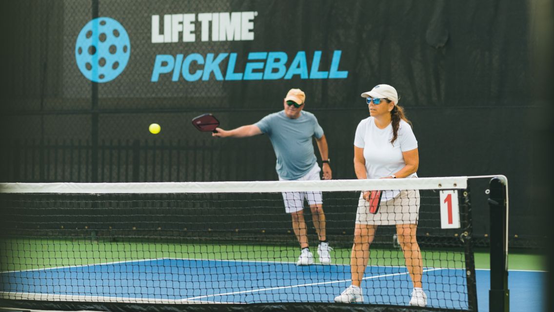 A man and a woman playing pickleball at Life Time.