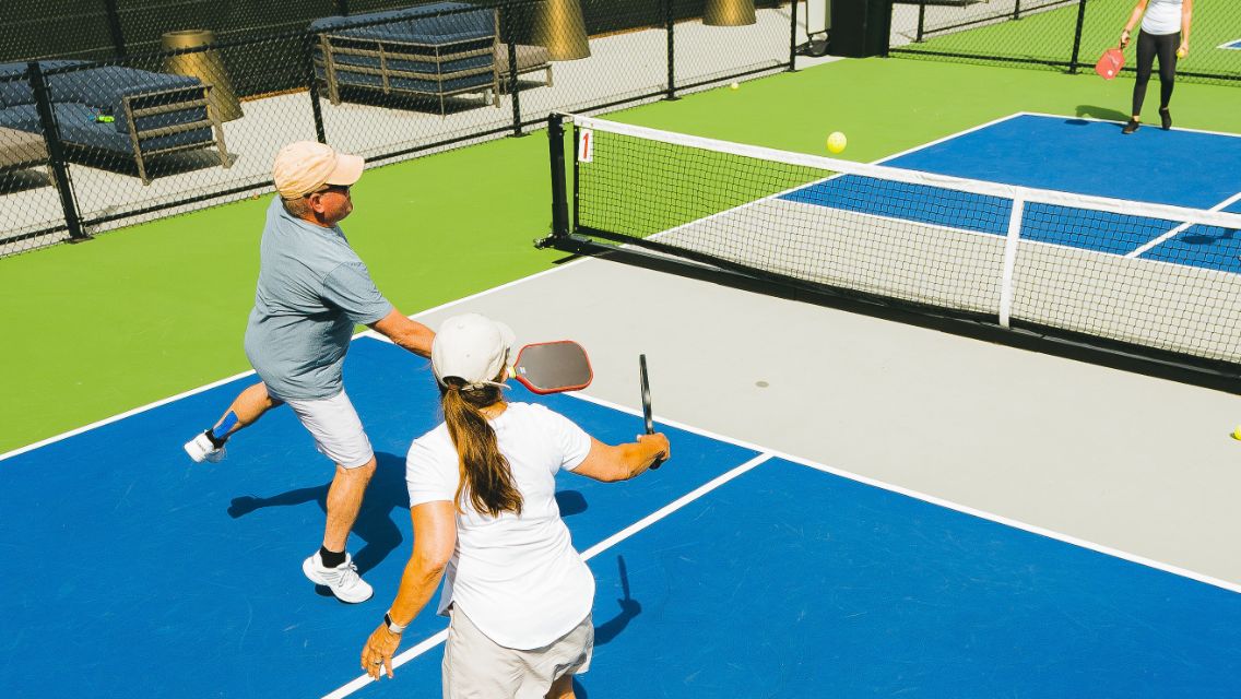 A man and a woman playing pickleball on an outdoor court.
