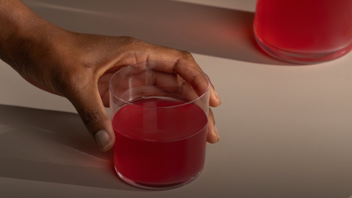 A person's hands holding a glass of LTH Pump Pre-Workout mixed in with water.