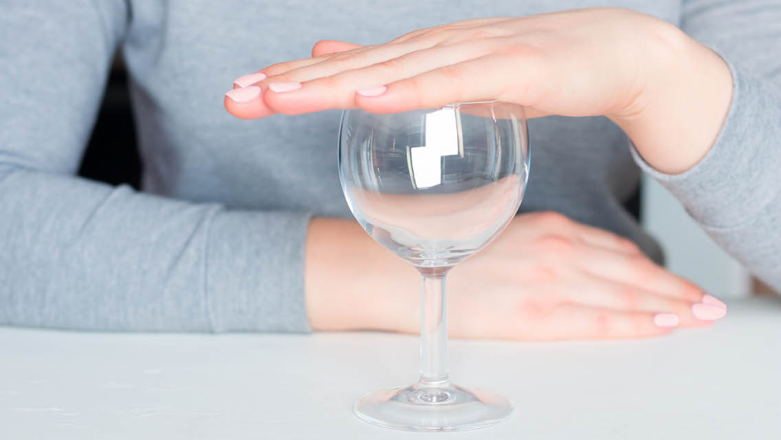 a person holds their hand over an empty wine glass