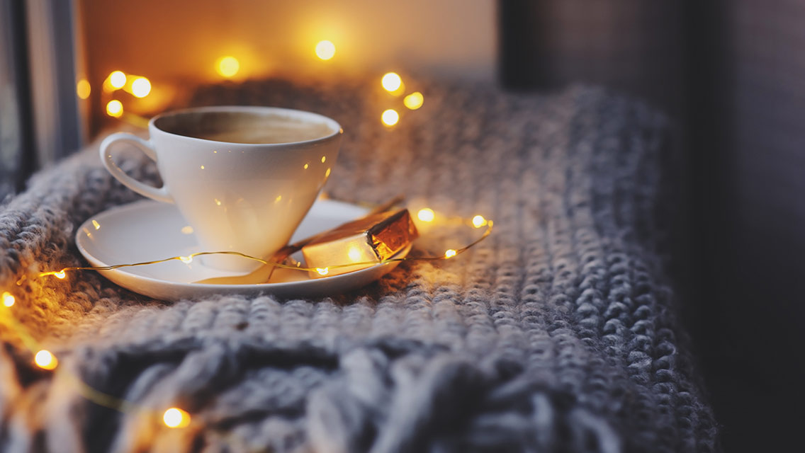 A cup of tea and a chocolate on a cozy gray blanket