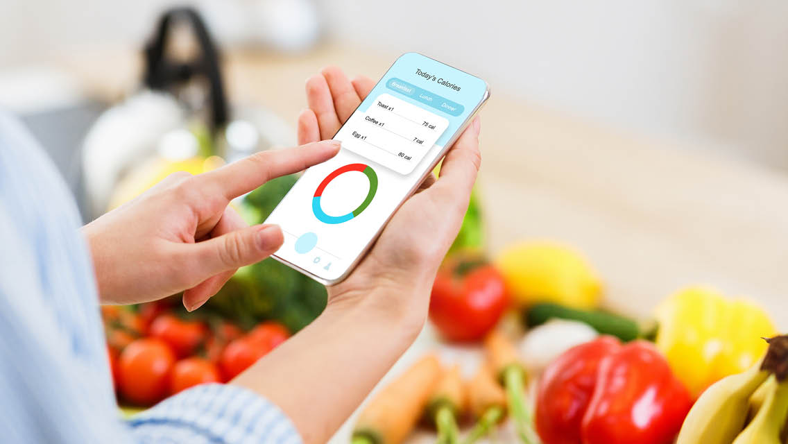 a woman holds her smart phone with fresh food in the background
