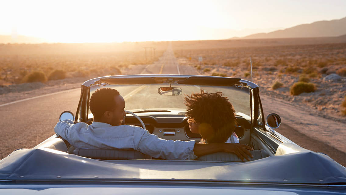 a couple drives in a convertibles down a dessert highway