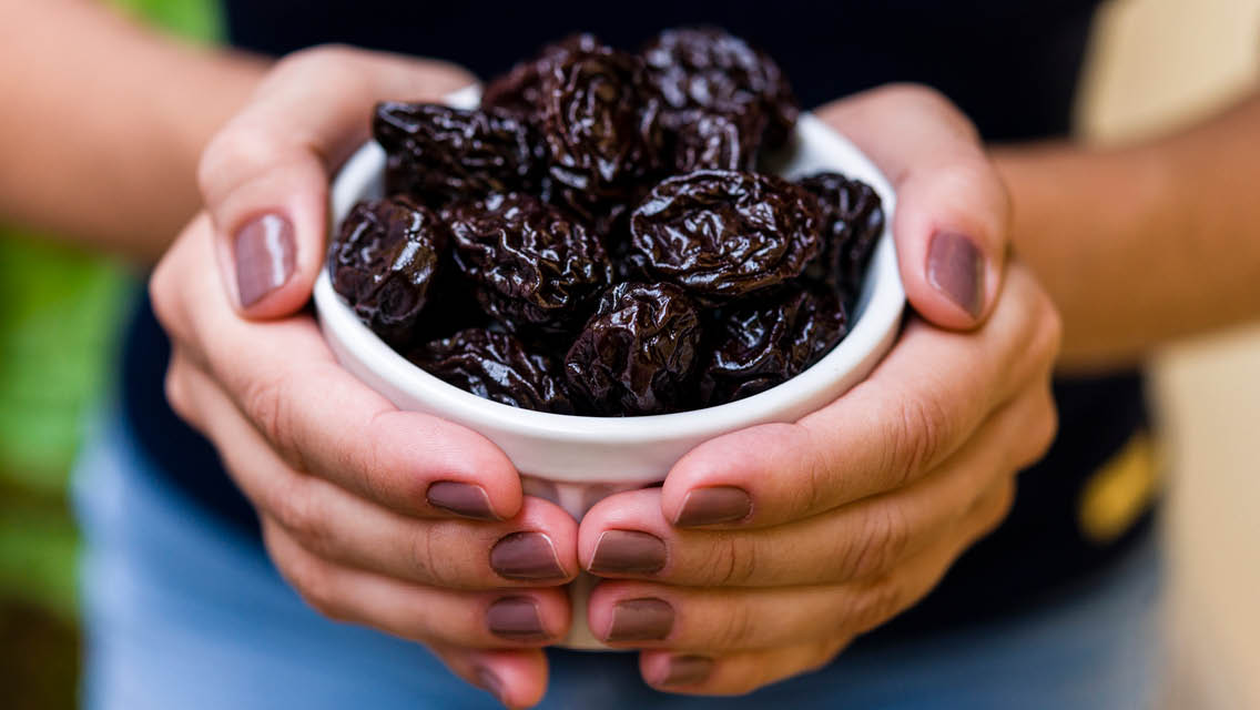 a woman holds a bowl of prunes