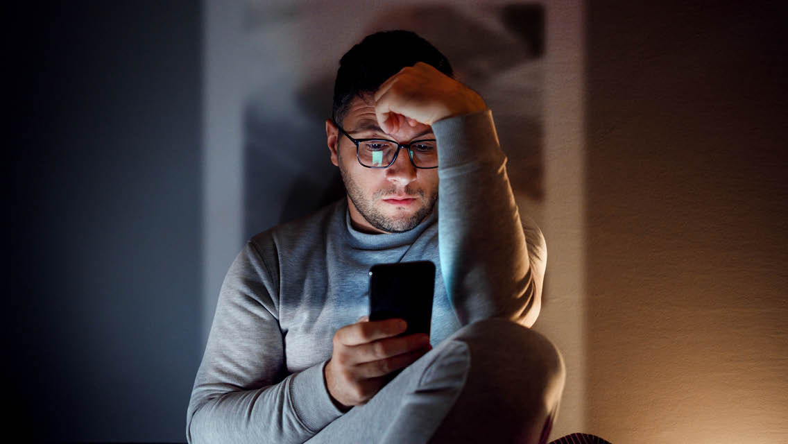 a man looks at his phone in a dark room