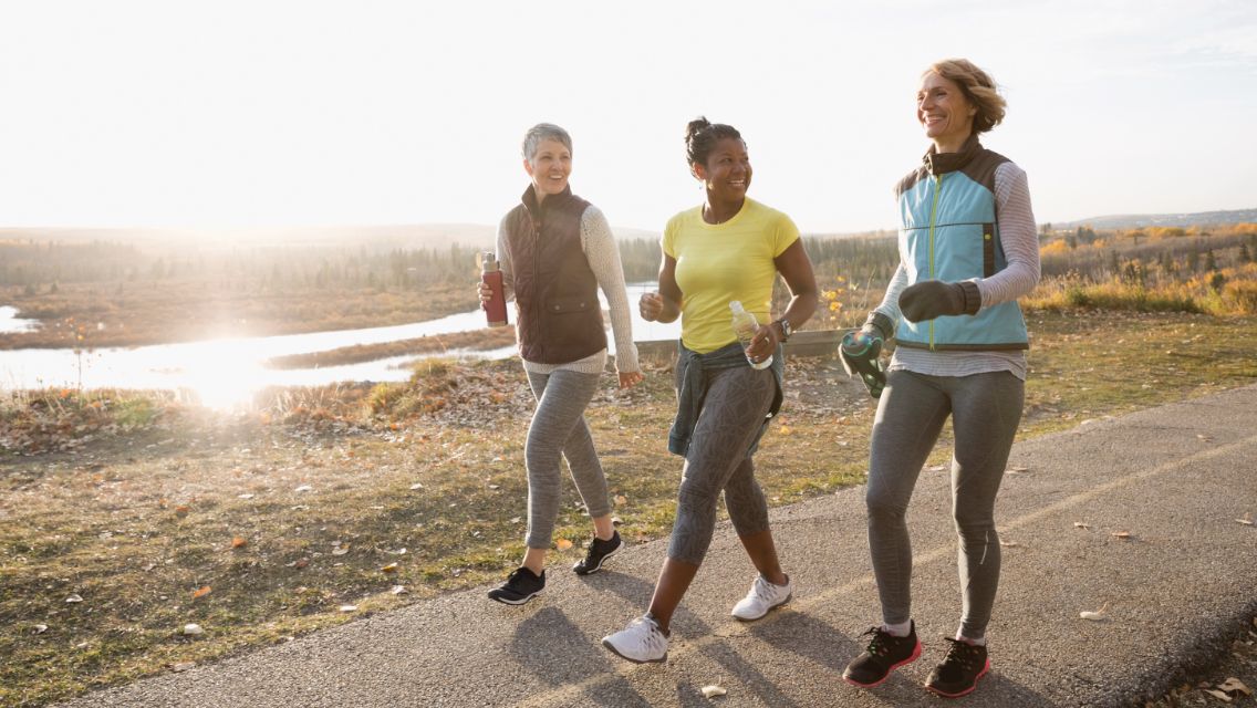 Three people in active-wear walking on a trail outdoors