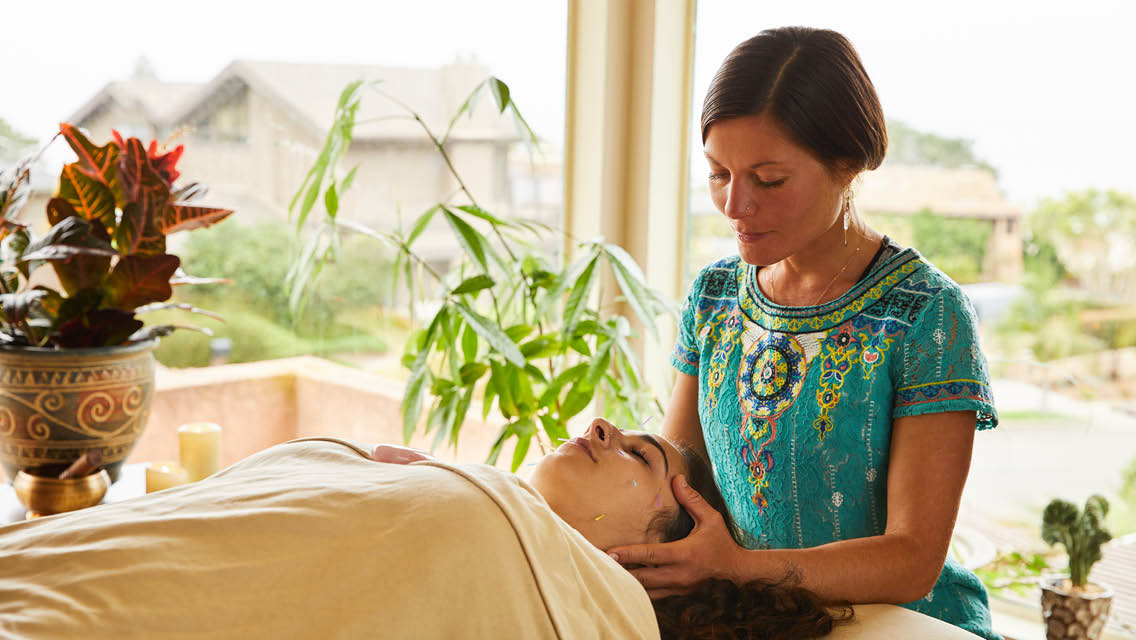 an energy healer holds her hands on client's head