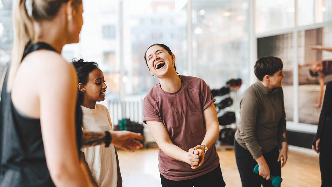 a woman laughs while taking a group fitness class