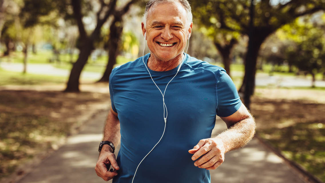 an older man jogging while smiling