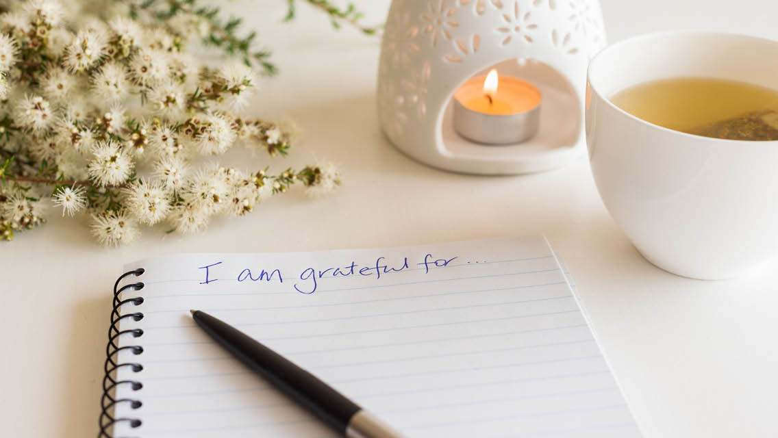a gratitude journal sits next to a cup of tea