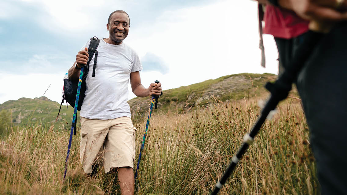 a man walks on a nature trail with walking poles