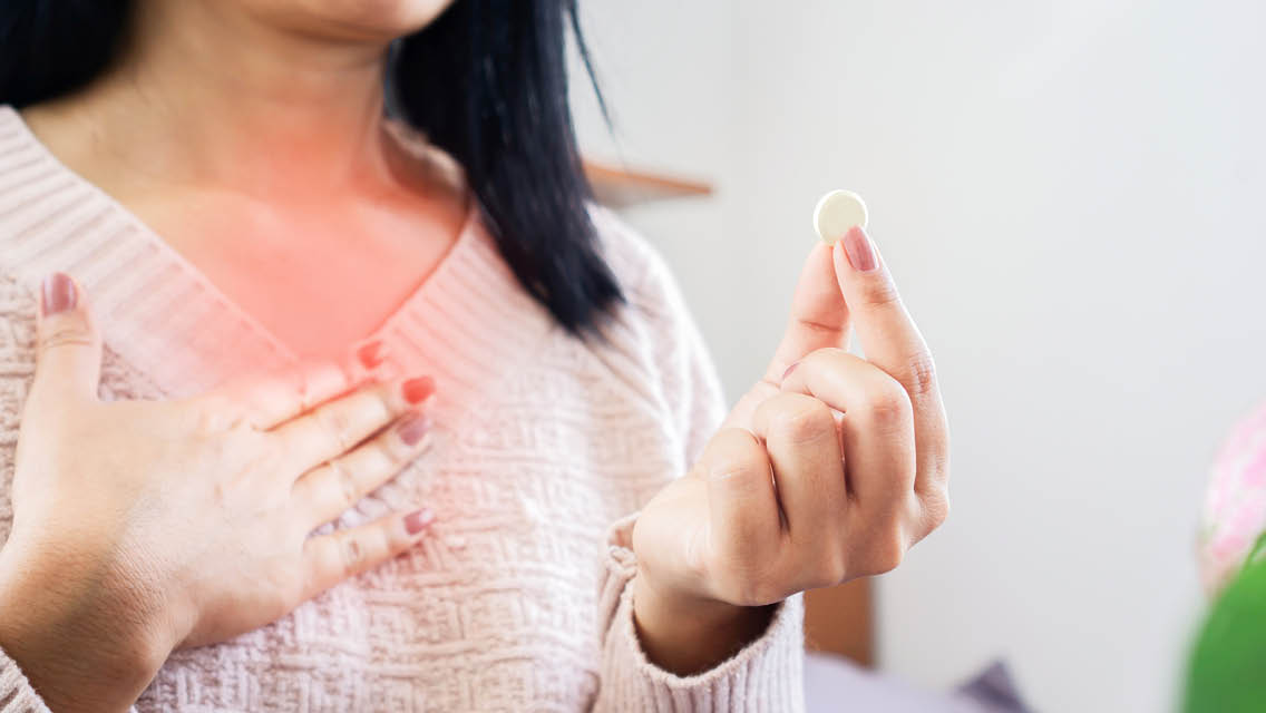 a woman holds an antacid with red over her chest