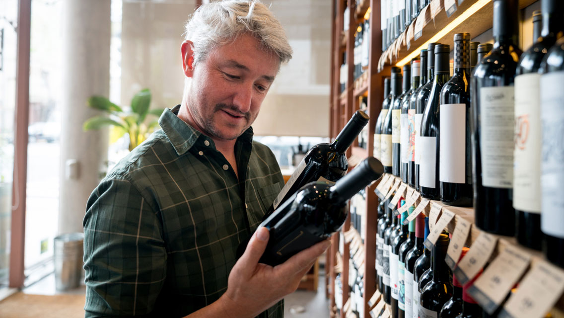 a man looks at a bottle of wine