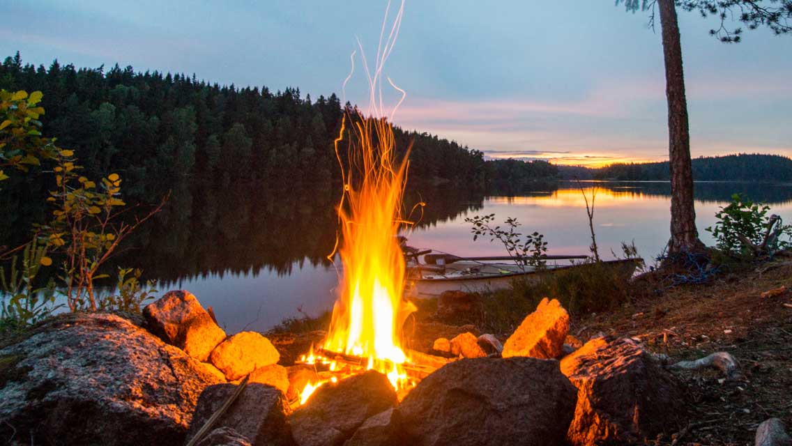 A picture of a roaring campfire next to a river.