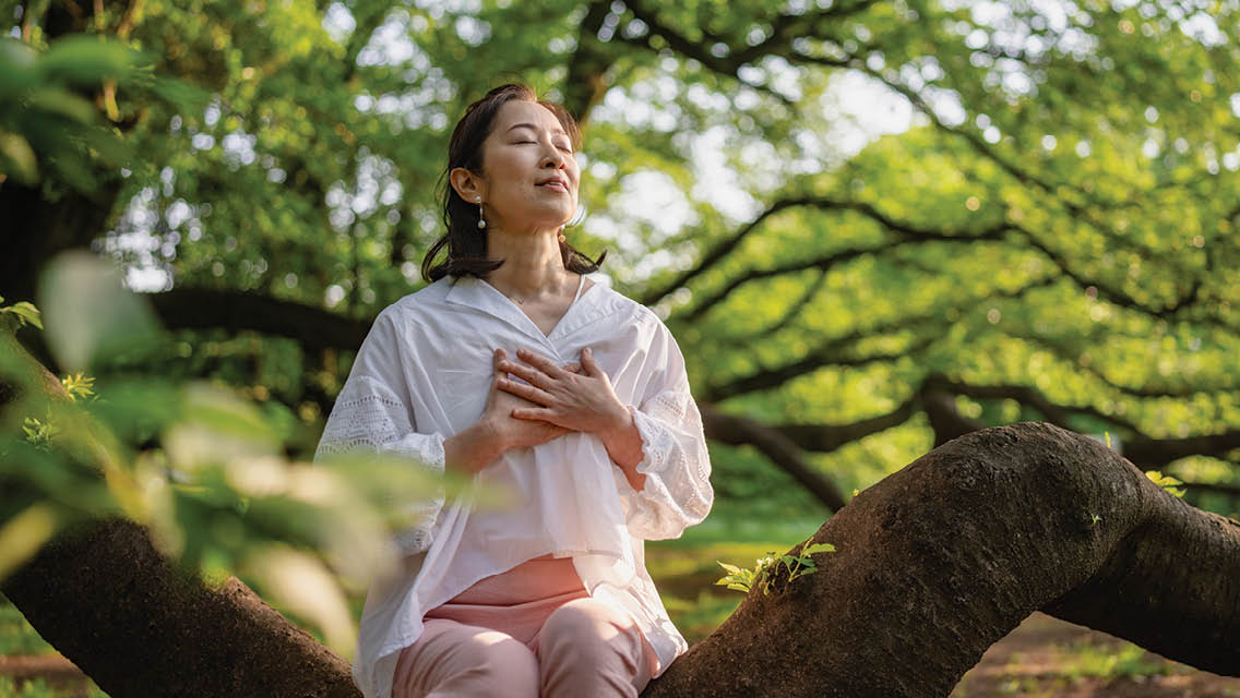 a woman sits and meditates in a forest