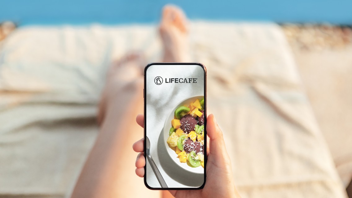 A person lounging on a poolside chair ordering food via their phone from the LifeCafe.