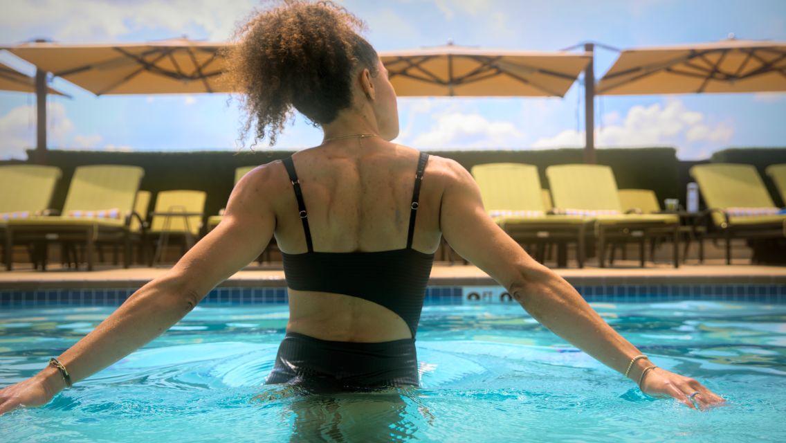A woman showing the back of her upper body and arms in a pool.