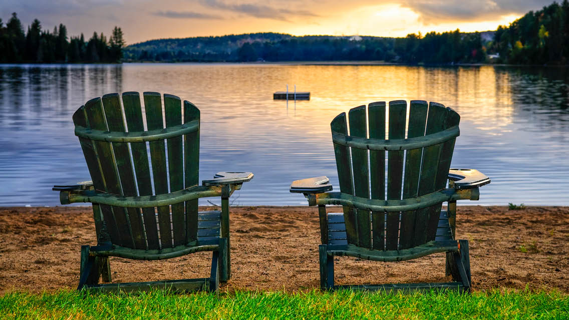 two chairs sit beach side at sunset