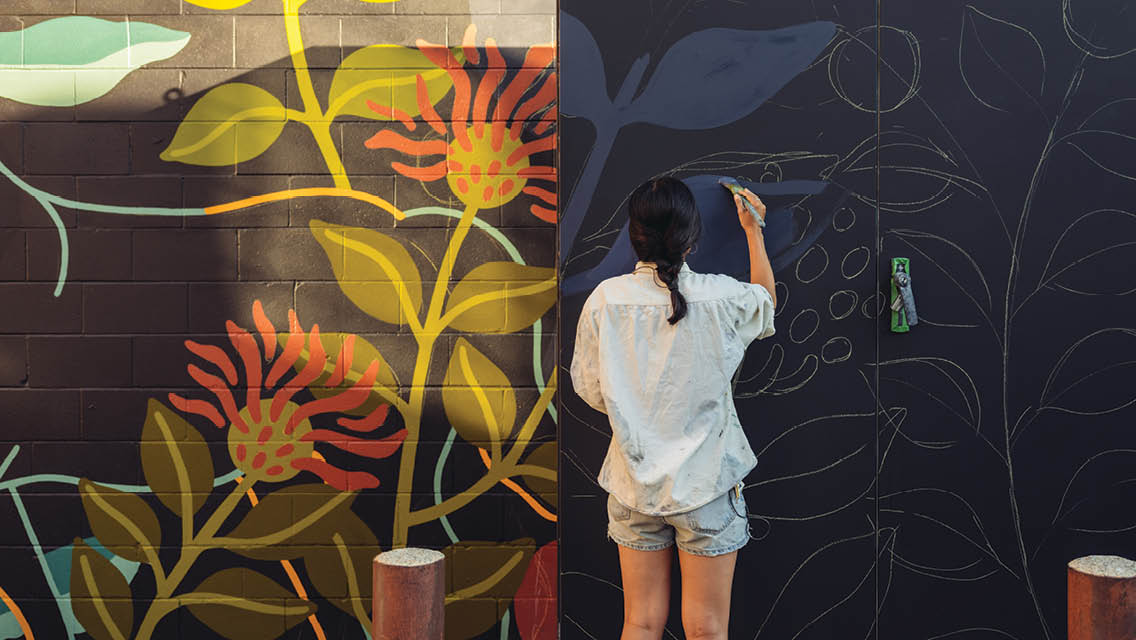 a woman paints a flower mural