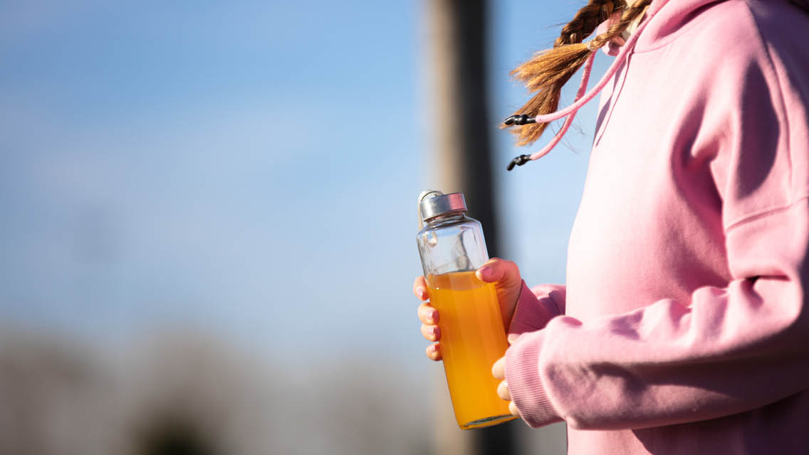 a person walks carrying a bottle with a sports drink