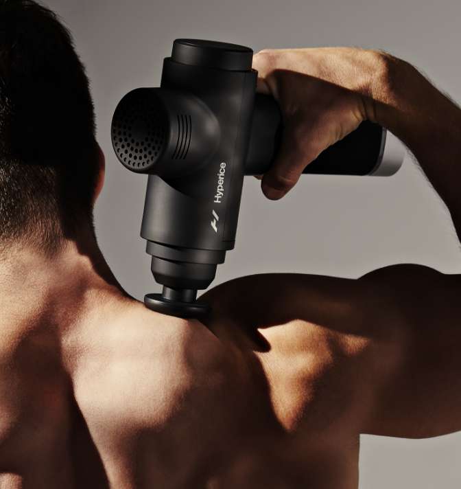 A man using a Hyperice device on his shoulder.