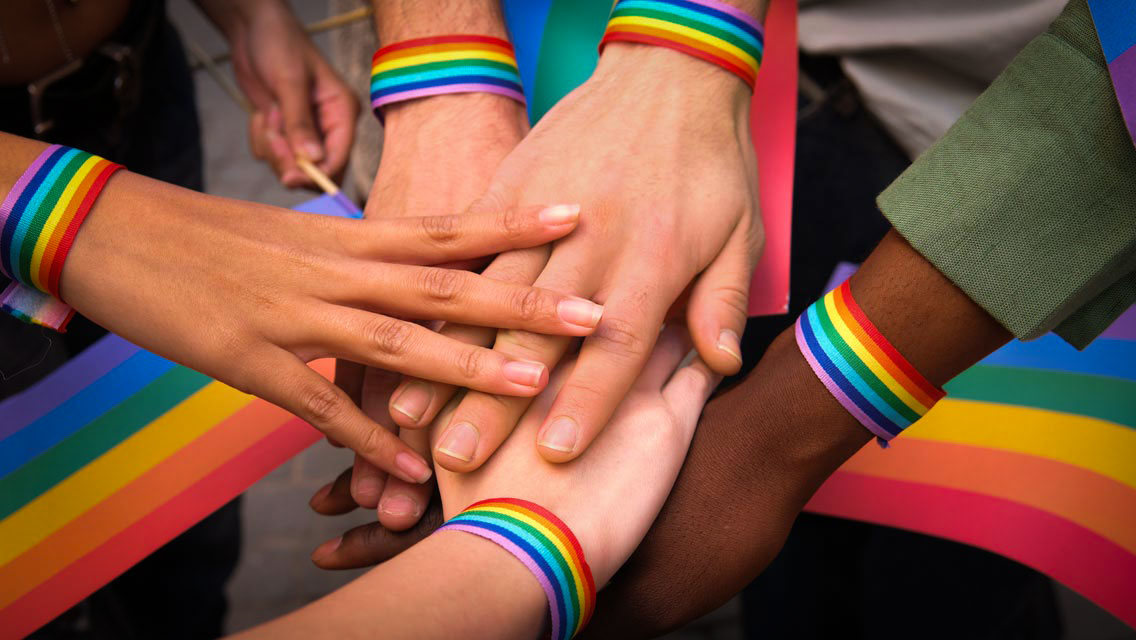 various hands wearing rainbow bracelets