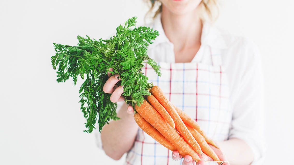 a person holds a bunch of carrots