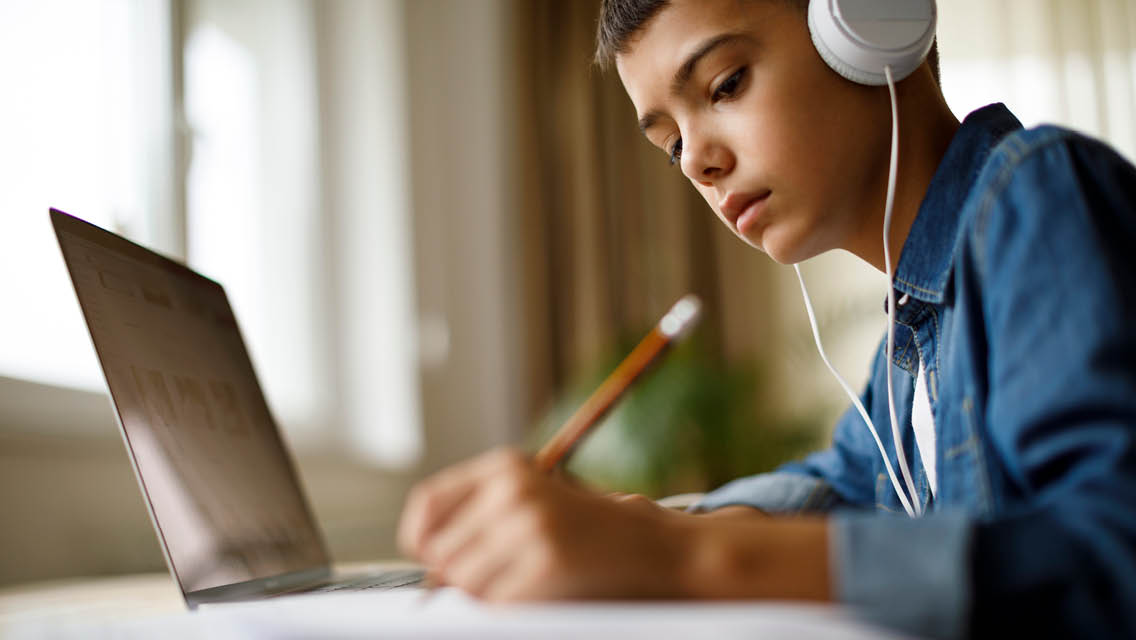 a child works while listening to music on headphones