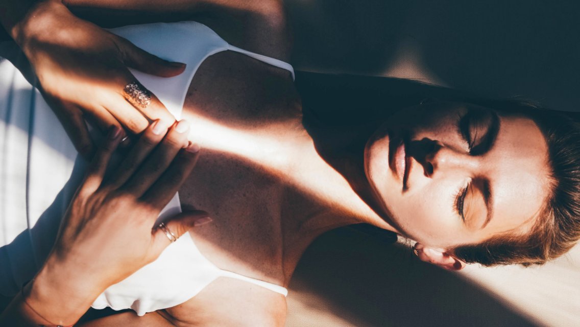 A woman lying down and breathing with her hands on her chest.
